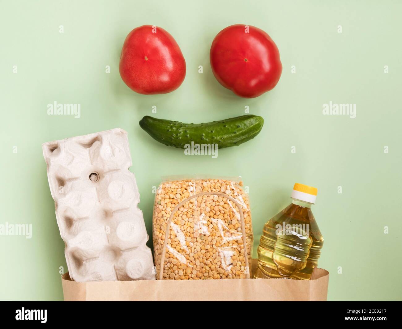 Lächelndes Gesicht aus Tomaten und Gurke auf Papiertüte Mit dem Essen Stockfoto