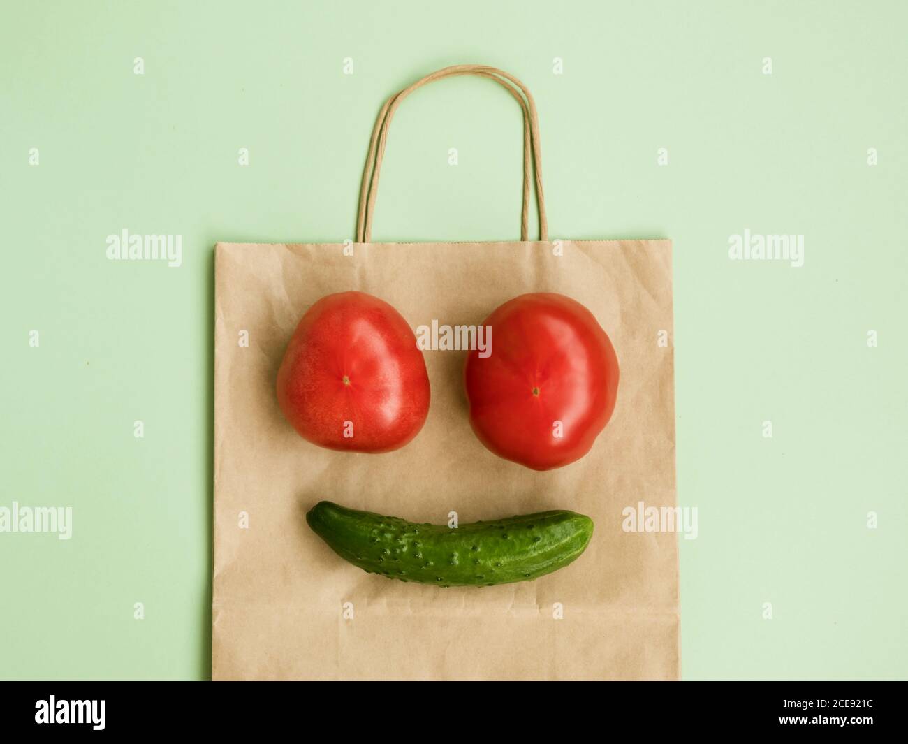 Lächelndes Gesicht aus Tomaten und Gurke auf Papiertüte Stockfoto