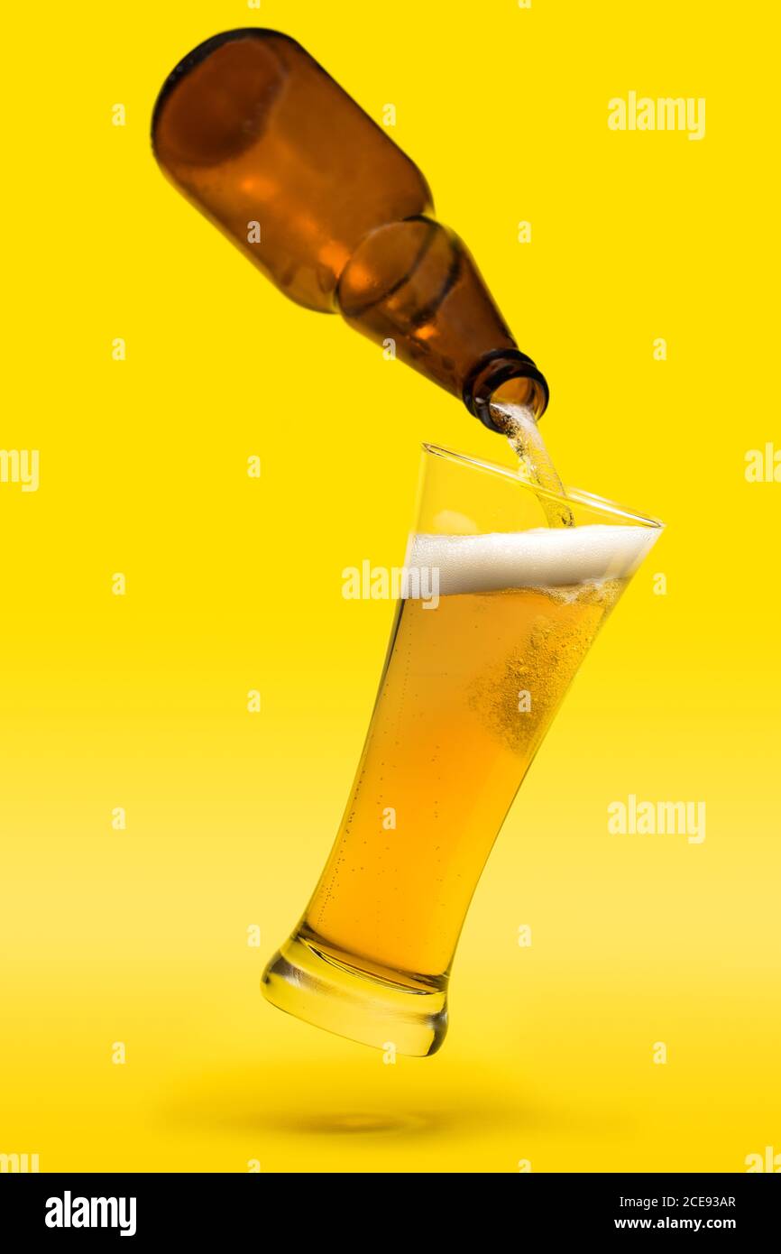Schwimmende Glas- und Bierflasche auf gelbem Hintergrund Stockfoto