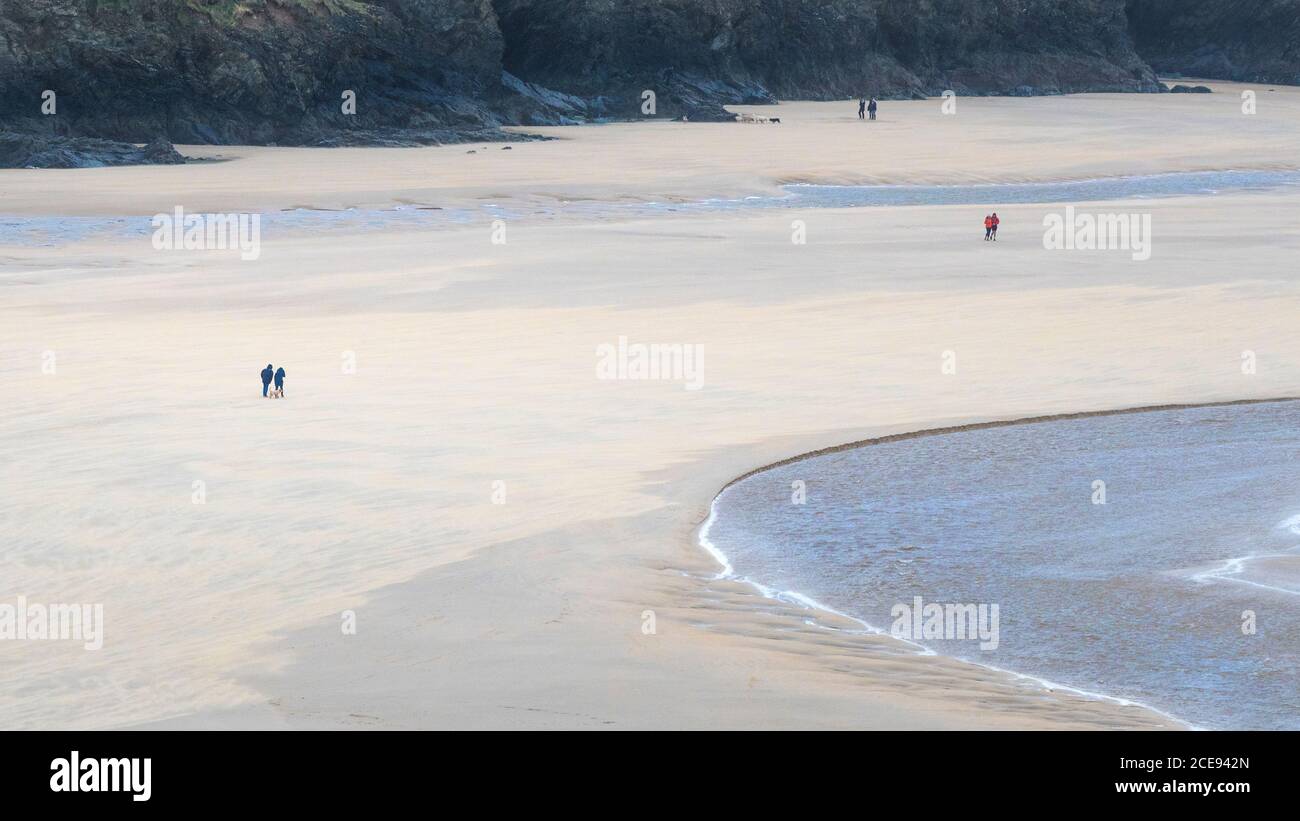 Ein Panoramablick auf die entfernten Figuren der Wanderer auf dem preisgekrönten Crantock Beach bei Ebbe in Newquay in Cornwall. Stockfoto