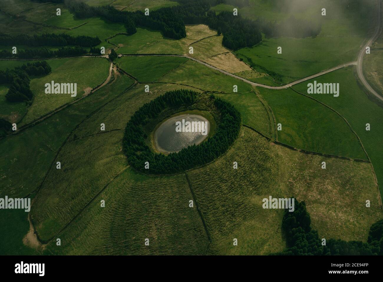 Luftaufnahme von kleinen See umgeben von grünem Wald und Großes Feld Stockfoto