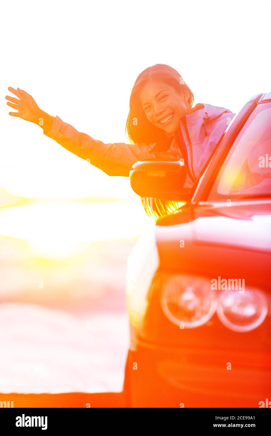 Roadtrip Reise Spaß junge asiatische Frau glücklich sorglos im Urlaub Sommerferien in teuren roten Sportwagen. Mädchen mit Arm aus Cabrio Stockfoto