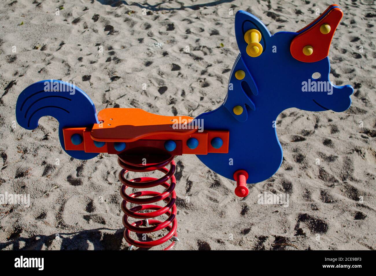 Spielen Gerät Einhorn Wippe. Ein blaues Einhorn mit einem roten Horn und einem orangefarbenen Sitz. Stockfoto