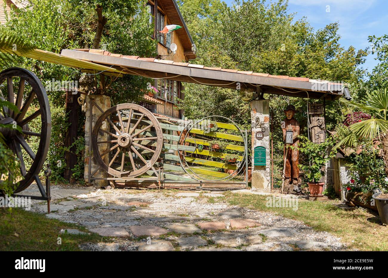 Tor mit alten hölzernen Rad und Bronzestatuen in einem ländlichen Haus geschmückt. Stockfoto