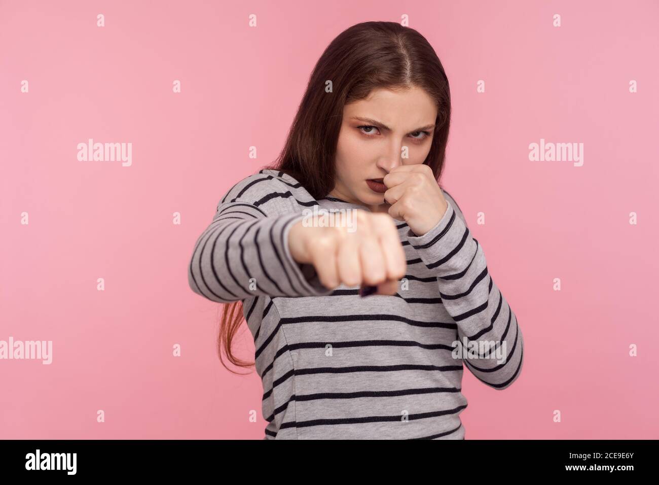 Komm schon, lasst uns kämpfen! Portrait von aggressiven wütenden Frau im gestreiften Sweatshirt Boxen zur Kamera, Stanzen und bedrohen Feind, bereit zu kämpfen. In Stockfoto