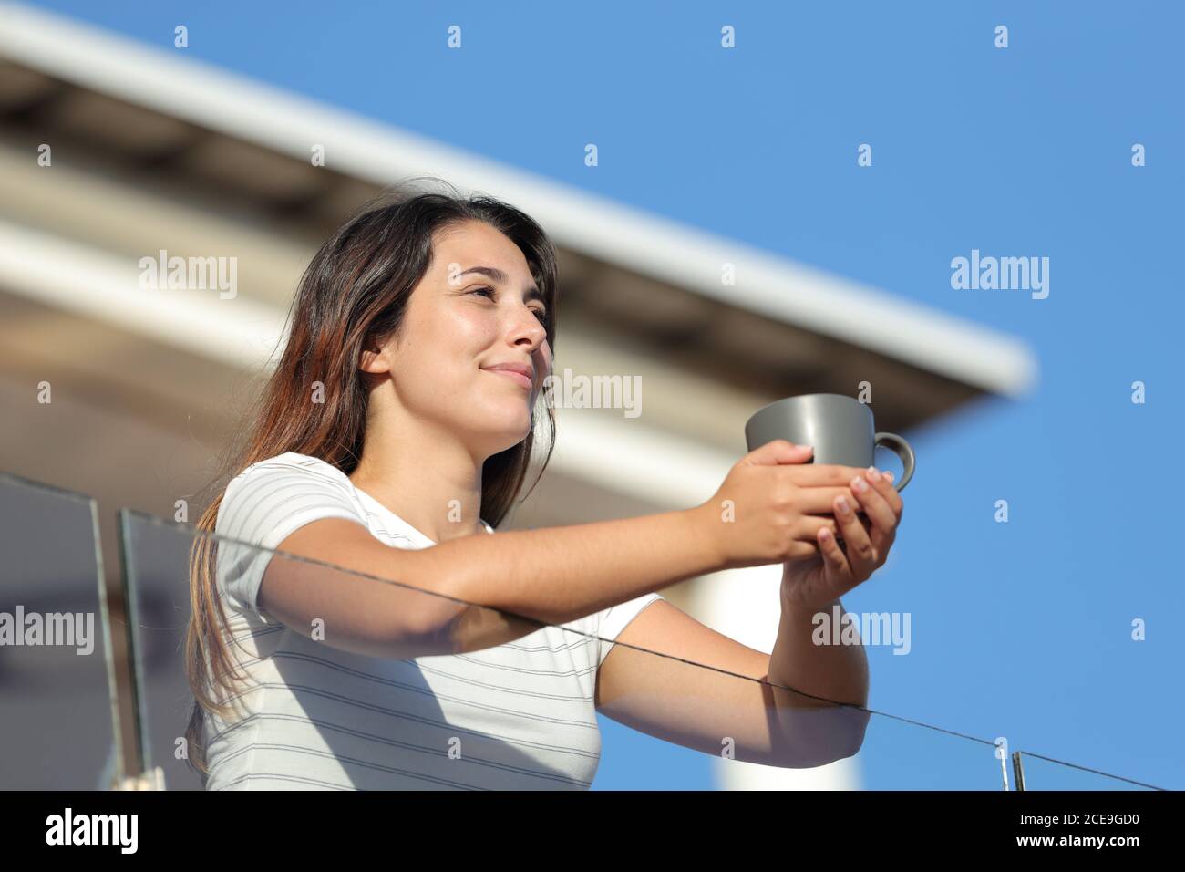 Gast Frau hält Kaffeetasse betrachten Aussicht vom Balkon der Wohnung Im Sommer Stockfoto