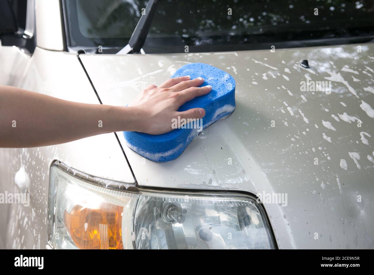 Ein Mann, der zu Hause Auto mit blauem Schwamm wäscht Stockfoto