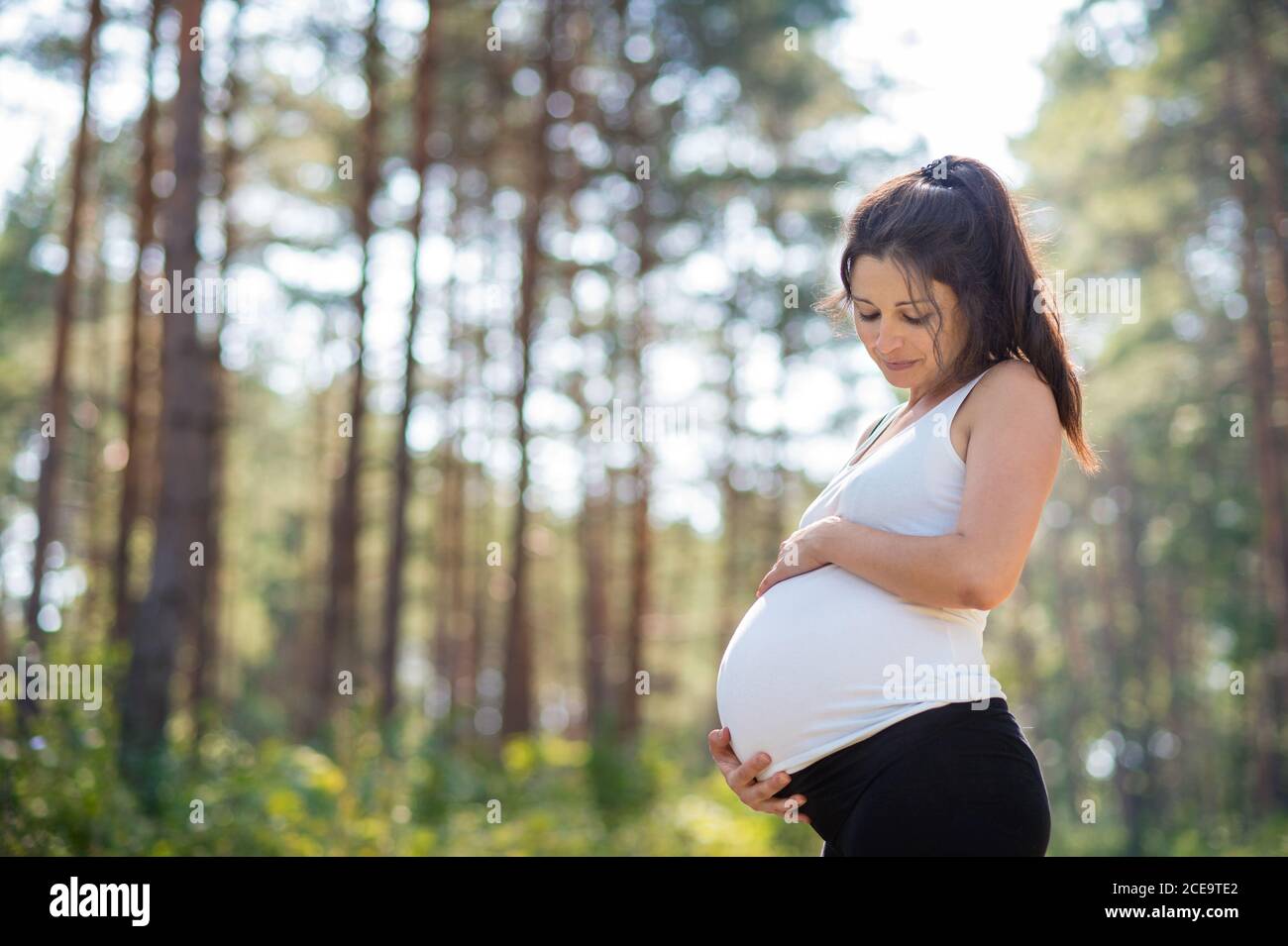 Porträt einer glücklichen schwangeren Frau im Freien in der Natur, berühren ihren Bauch. Stockfoto