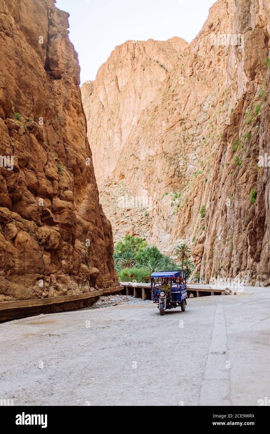 Blaues Fahrzeug auf einsamer Straße in sandiger Schlucht. Vertikale Außenaufnahme. Stockfoto