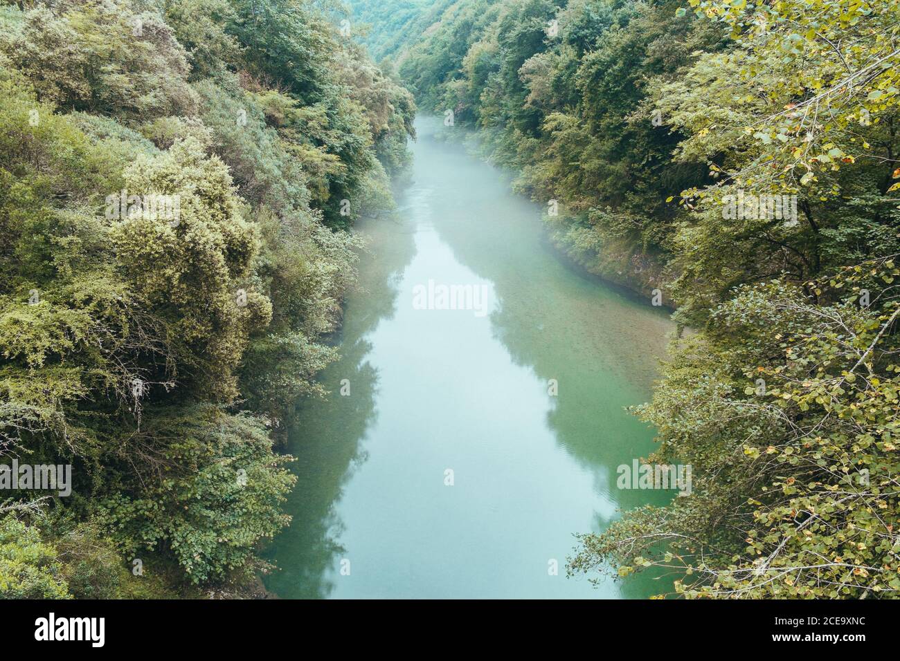 Von oben von blauem Wasser mit Dunst über fließt langsam zwischen Küsten mit üppiger Vegetation, Asturien Stockfoto