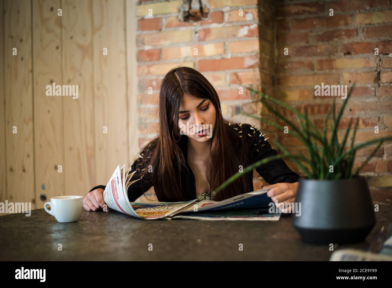 Junge Frau beim Lesen der Zeitung im Café Stockfoto
