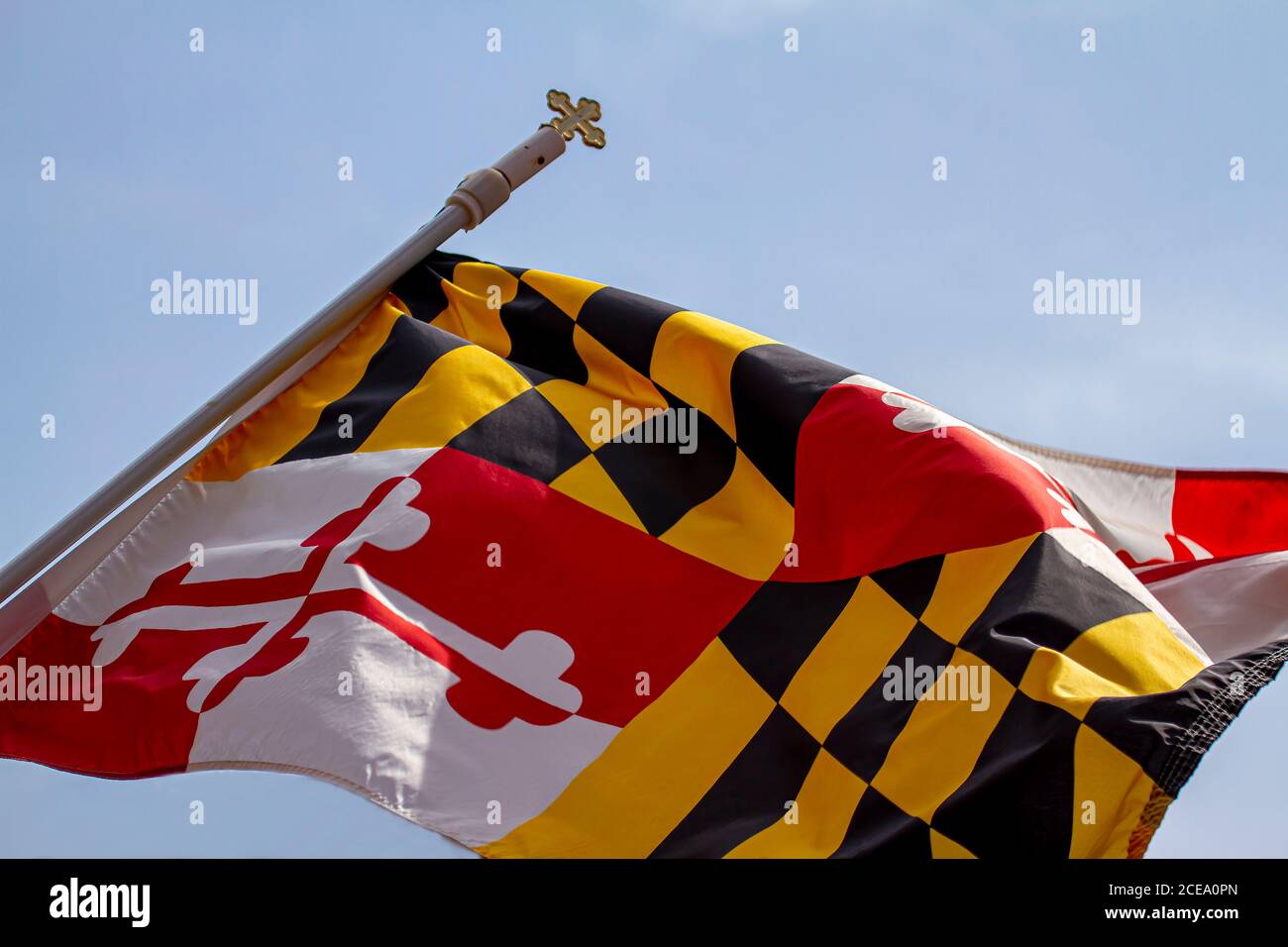 Isoliertes Nahaufnahme-Foto der Maryland State Flag gegen klaren Himmel. Die Fahne ist an einem Pfosten mit einem Kreuz oben befestigt. Das einzigartige Design ist eine Kombination Stockfoto