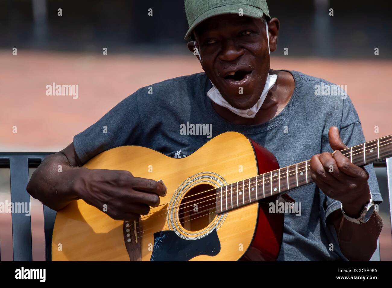 Annapolis, MD 08/21/2020: Ein älterer afroamerikanischer Mann, der Baseballhut und eine Gesichtsmaske trägt, spielt klassische Gitarre und singt, während er o sitzt Stockfoto