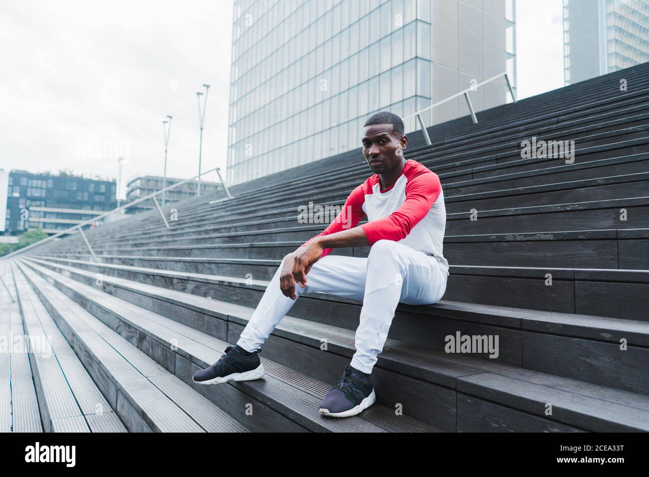 Ethnischer Mann, der nach dem Training auf der Treppe ruht Stockfoto