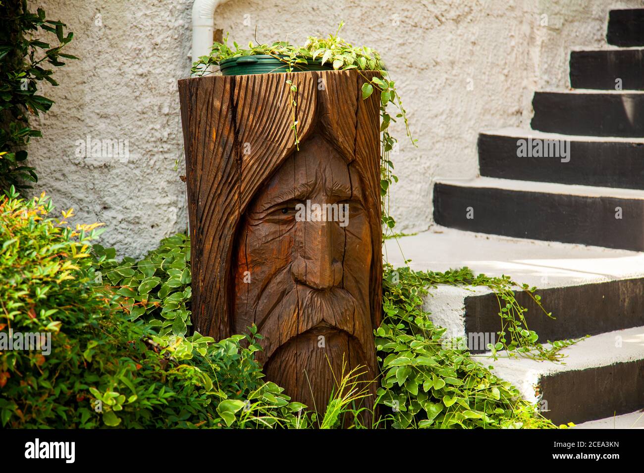 Annapolis, MD 08/21/2020: Ein Garten mit Steintreppe und Holzbalken als Topfhalter. Das Holz ist in den Eindruck eines alten Mannes geschnitzt Stockfoto
