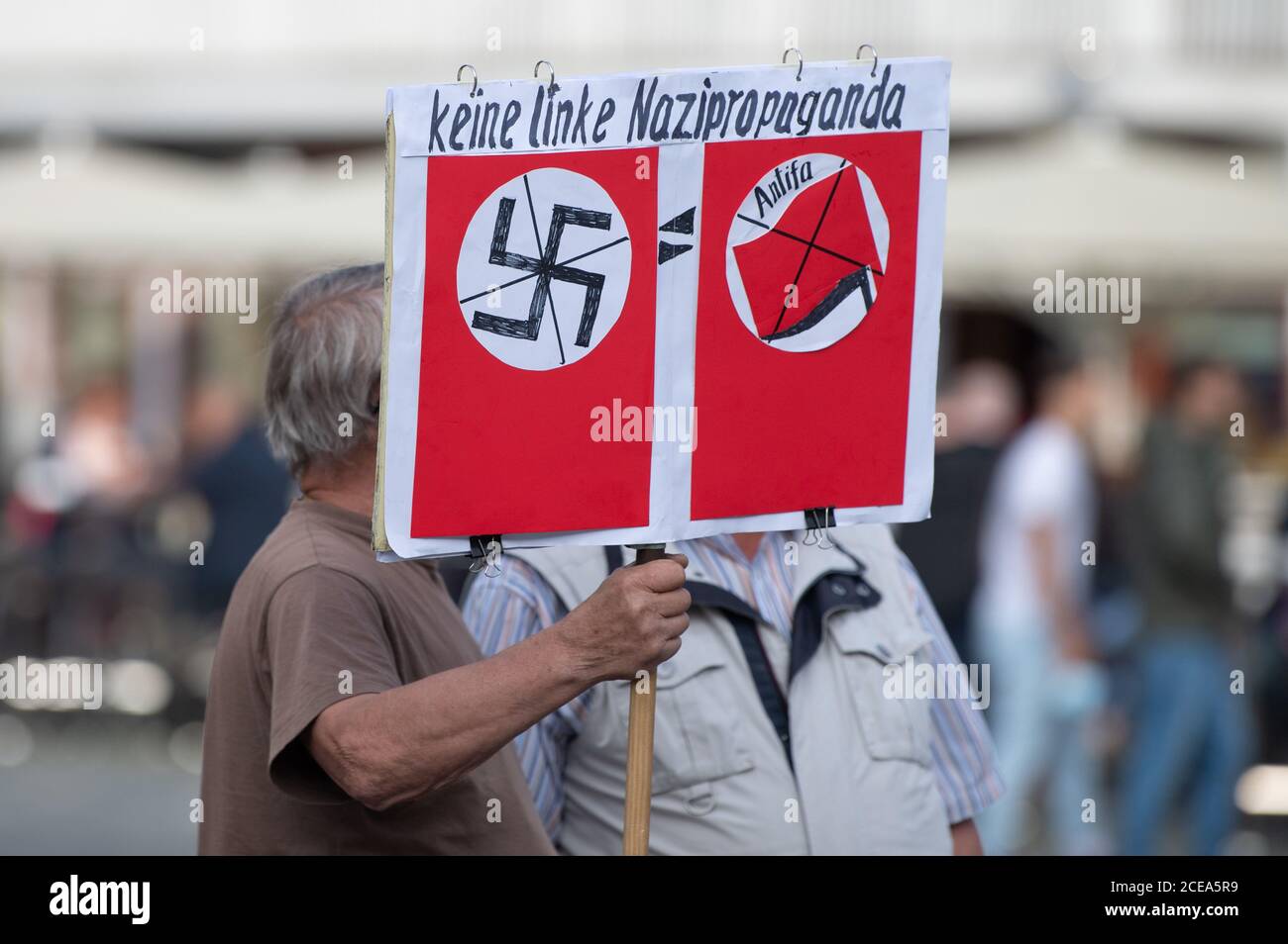 Dresden, Deutschland. August 2020. Ein Teilnehmer einer Kundgebung der islamisch- und fremdenfeindlichen Pegida-Bewegung hält am Neumarkt ein Schild mit durchgestrichenen Hakenkreuzen, durchgestrichenen Antifa-Bildern und der Aufschrift "Keine linke Nazi-Propaganda". Quelle: Sebastian Kahnert/dpa-Zentralbild/dpa/Alamy Live News Stockfoto