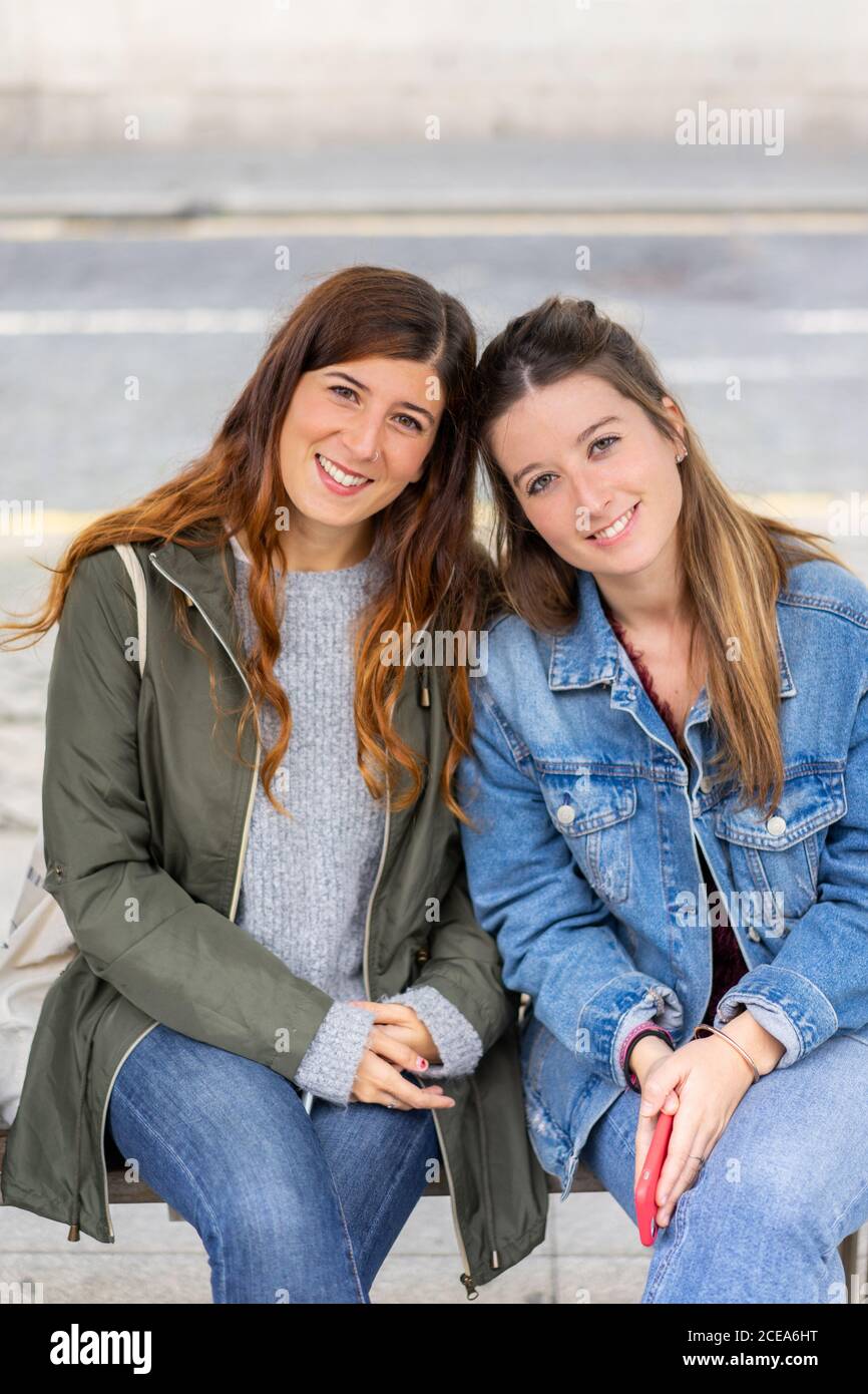 Junge Damen in legerer Kleidung sitzen auf der Bank Stockfoto