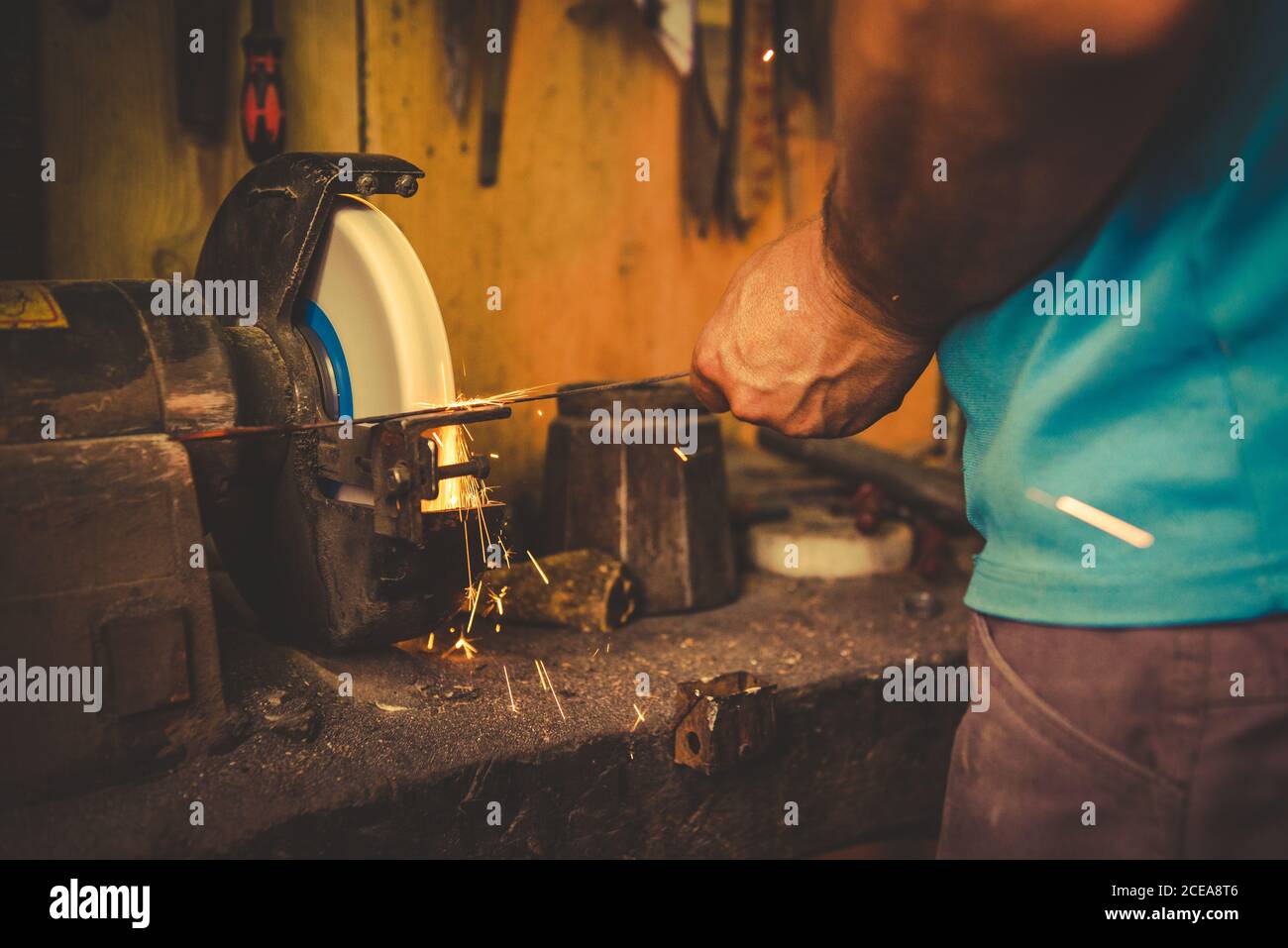 Crop smith mit Schleifstein zum Schleifen Metallklinge im professionellen Werkstatt Stockfoto