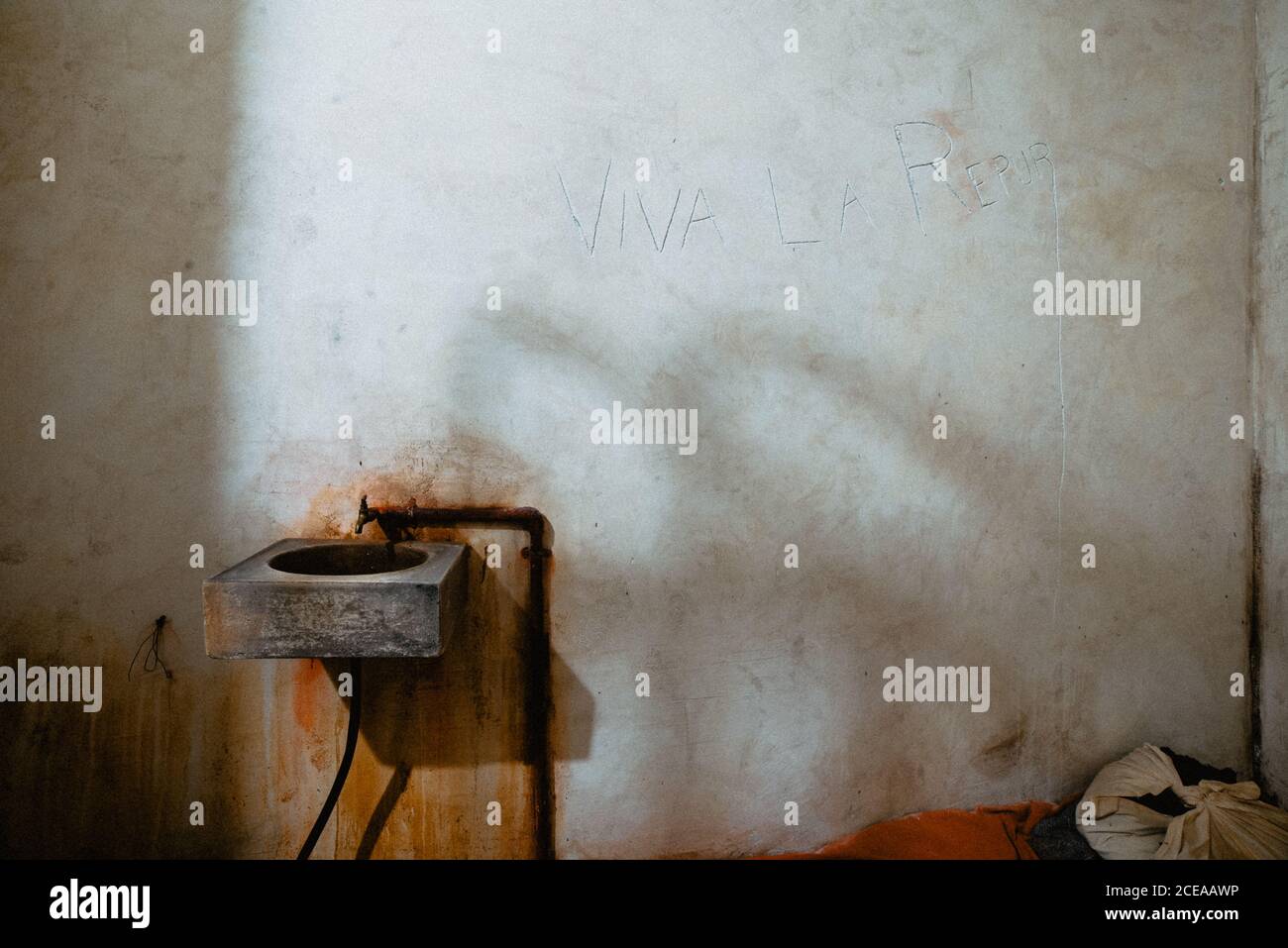 Schmutziges Waschbecken, das an einer schäbigen Betonwand einer alten Gefängniszelle in Oviedo, Spanien, befestigt ist Stockfoto