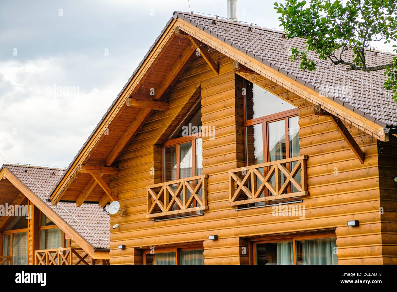 Modernes Holzhaus mit großen Fenstern und Balkon. Konzept des Baus von Familienhäusern, Pensionen oder Hütten auf dem Land. Bau von Häusern Stockfoto