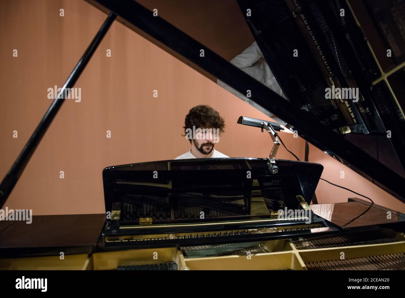 Schöner bärtiger Mann, der während der Probe im Aufnahmestudio Klavier spielt. Stockfoto