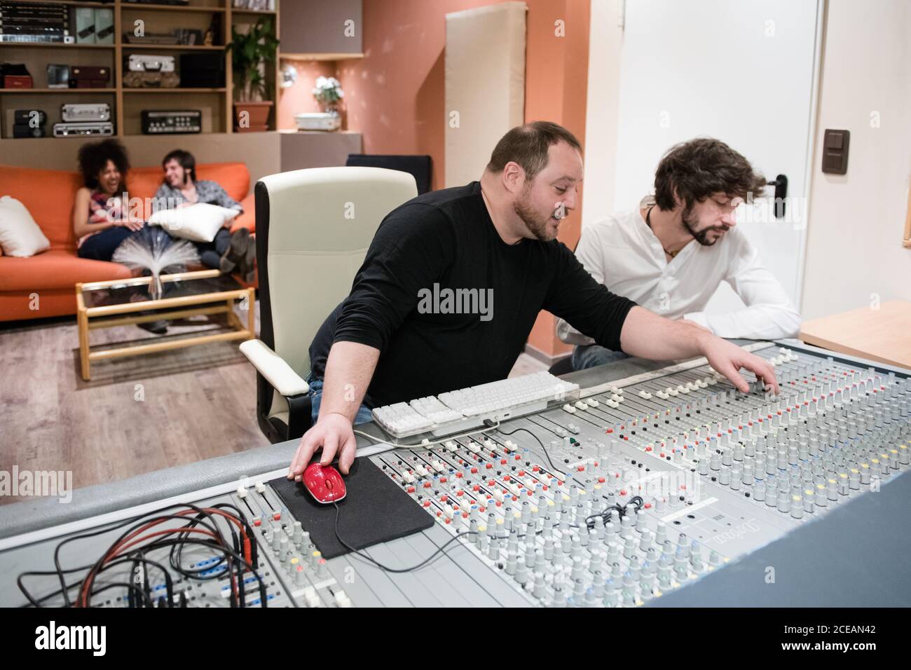 Zwei Sounddirektoren sitzen während der Arbeit am Audio-Mischpult Im modernen Aufnahmestudio Stockfoto