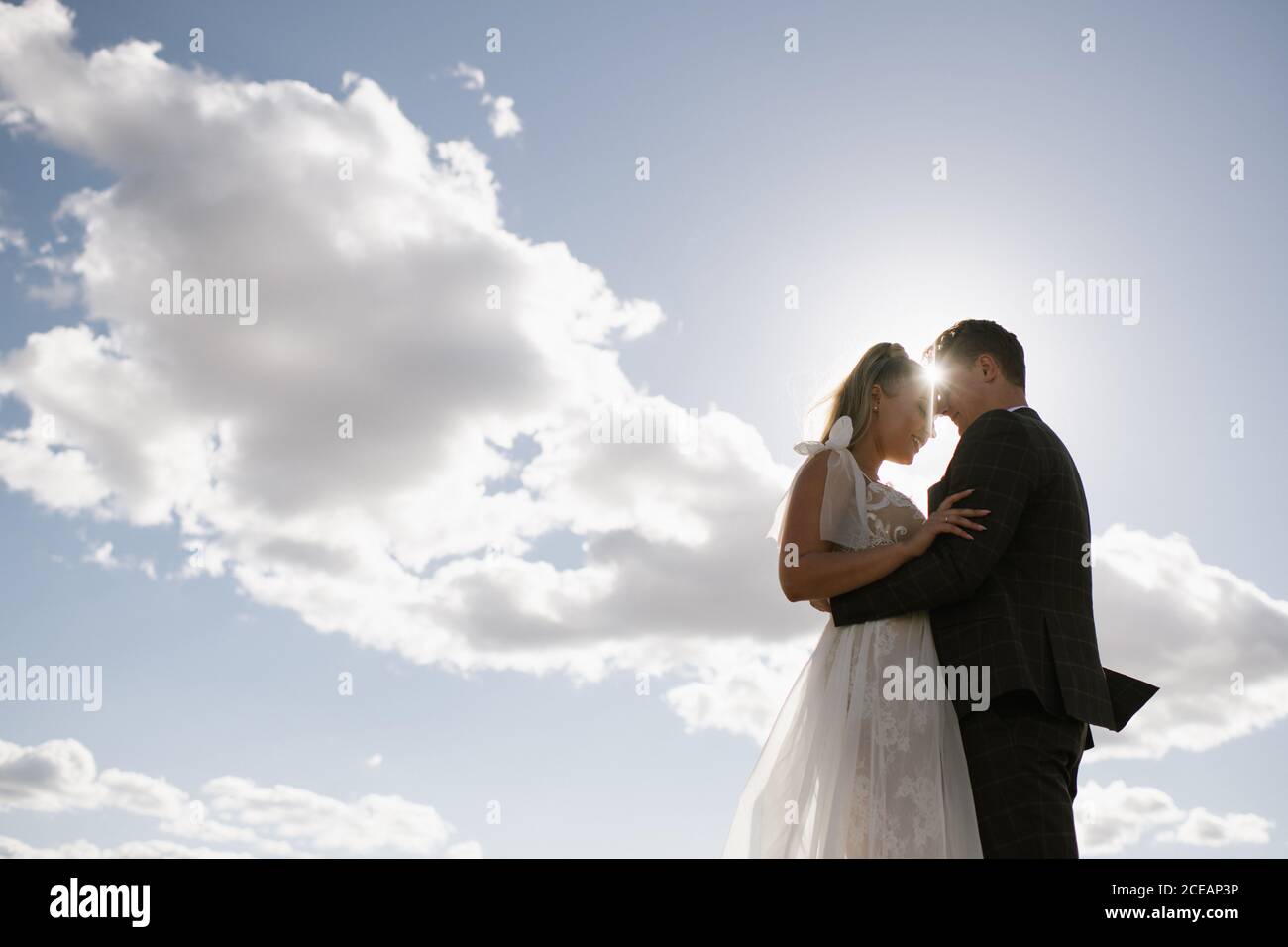 Braut und Bräutigam halten einander mit Himmel Hintergrund Stockfoto
