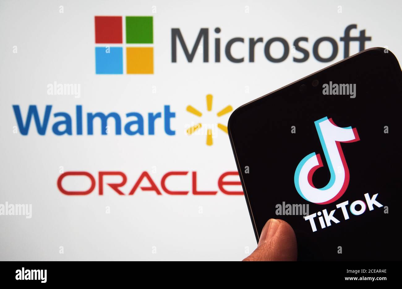 Stone / UK - August 31 2020: TikTok-Logo auf dem mobilen Bildschirm und verschwommene Logos von Microsoft, Walmart, Oracle auf dem verschwommenen Display auf der Rückseite. Nicht Stockfoto
