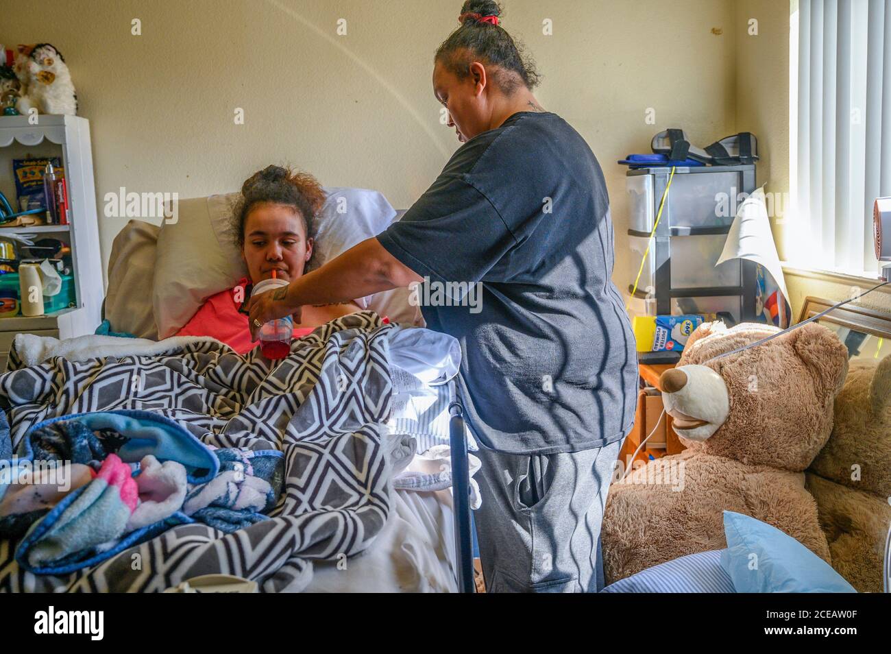 Sacramento, Kalifornien, USA. Februar 2019. Felicia Clark, 36, gibt ihrer Tochter Felicia Brent-Velasquez, 18, am Freitag, 14. Februar 2020, in Sacramento einen Drink Soda. Sie sagte, dass die Ärzte sagten, sie würde nie essen oder trinken oder nicht mit Sauerstoff versorgt werden, aber seit ihrer Rückkehr nach Hause hat sie all diesen Widrigkeiten trotzt. Brent-Velasquez sagte, sie sei stolz, dass sie ihren Katheter entfernen konnte und dass sie unter der Obhut ihrer Mutter keine Wundstellen mehr habe. Quelle: Renée C. Byer/ZUMA Wire/Alamy Live News Stockfoto