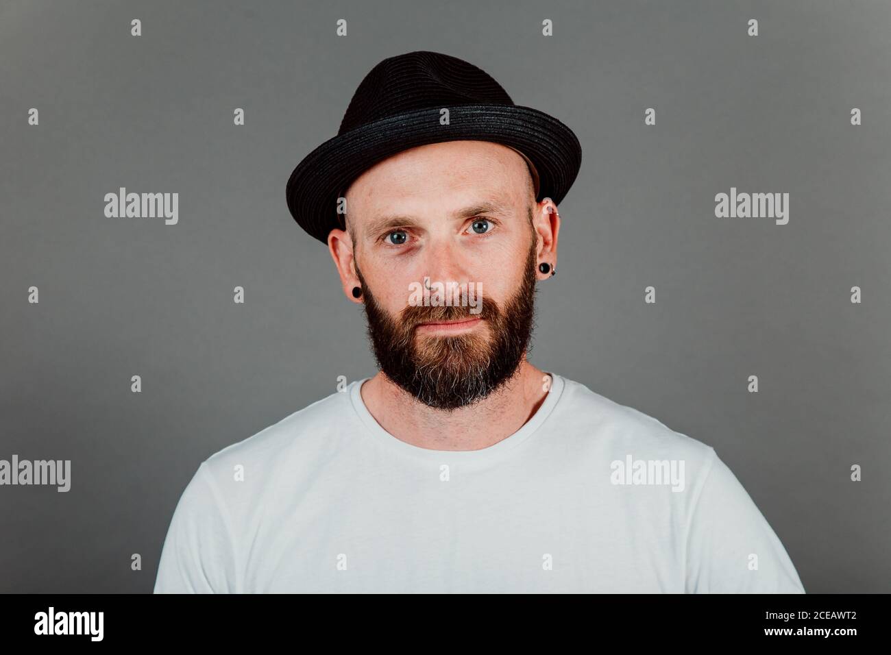 Unbehaarte Hipster in T-Shirt und Mütze mit Bart auf schwarzem Hintergrund Stockfoto
