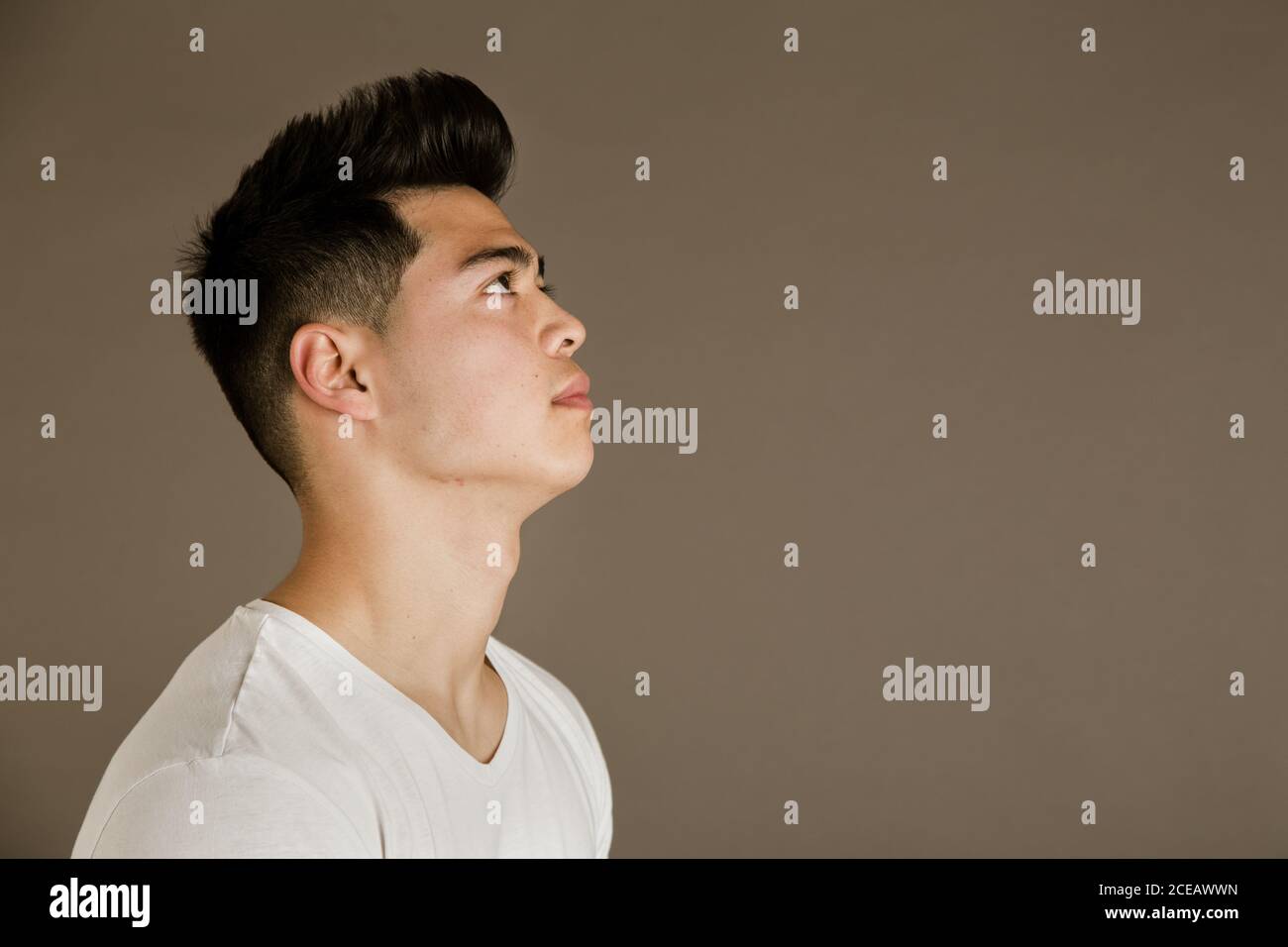Junger Mann sitzt auf einem Stuhl im Studio Stockfoto