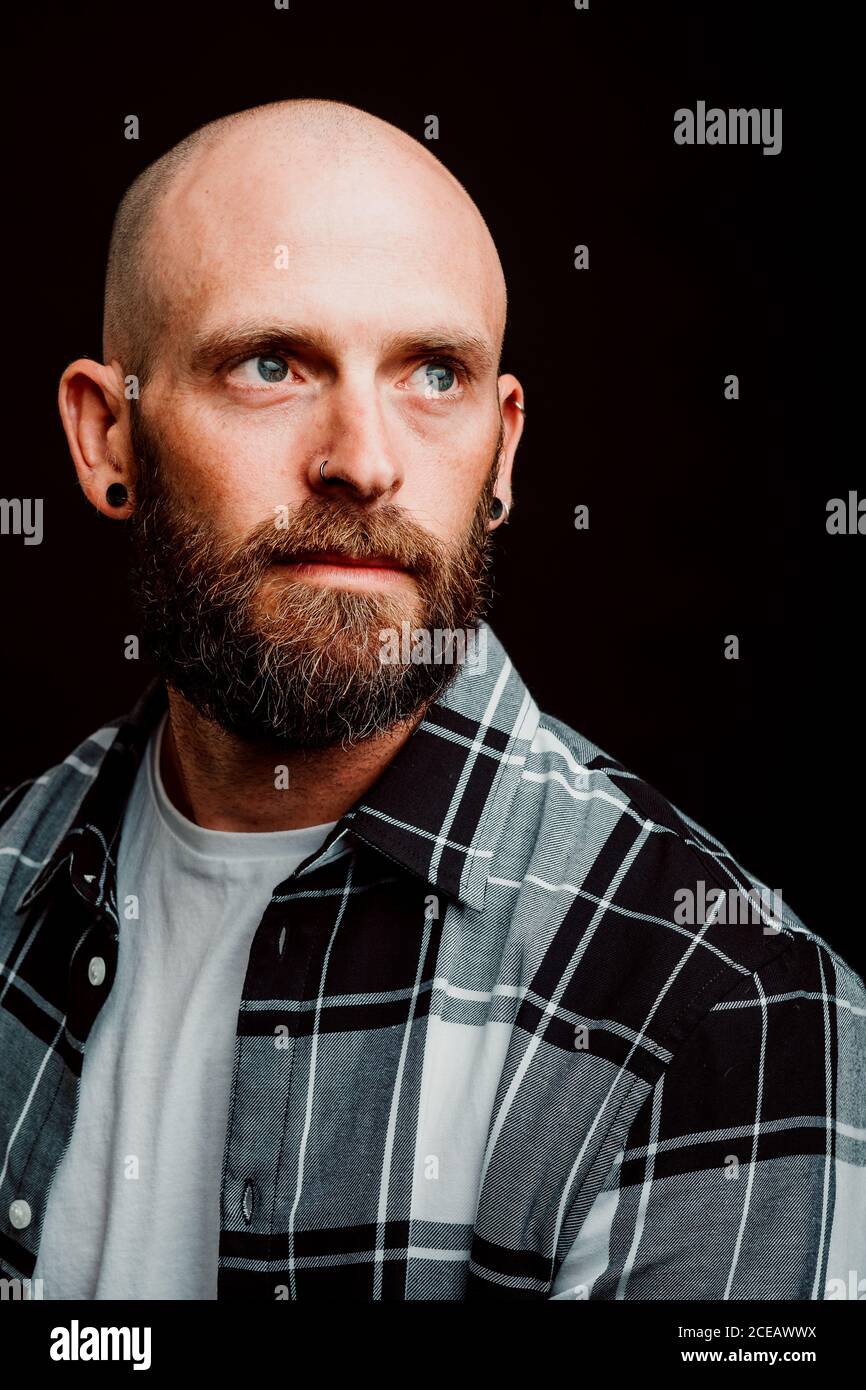 Bärtige haarlose Hipster in shirt Kamera schaut auf schwarzem Hintergrund Stockfoto