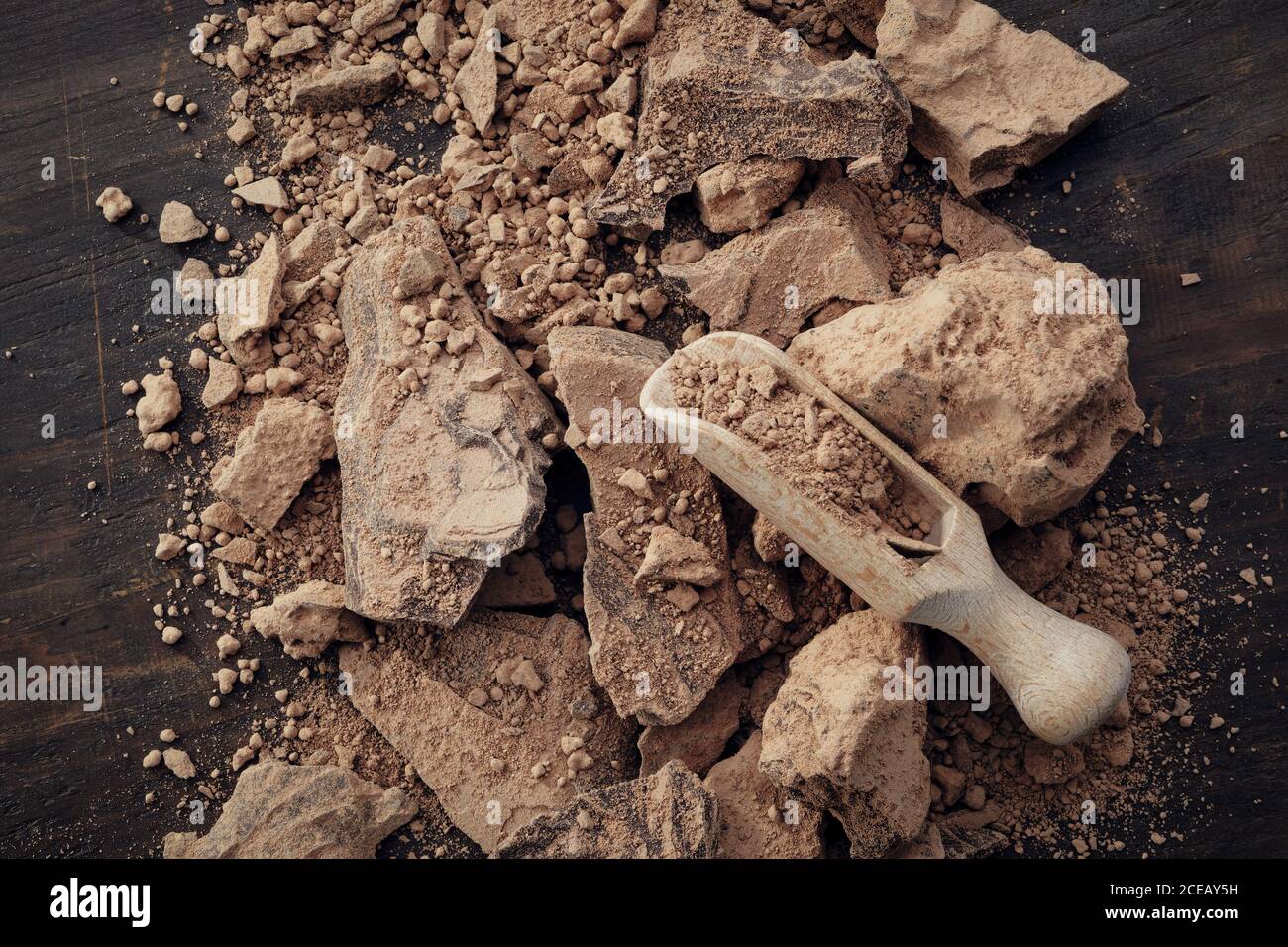 Stücke geriebener Kakao. Naturschokoladenklumpen und Holzlöffel, Draufsicht. Stockfoto