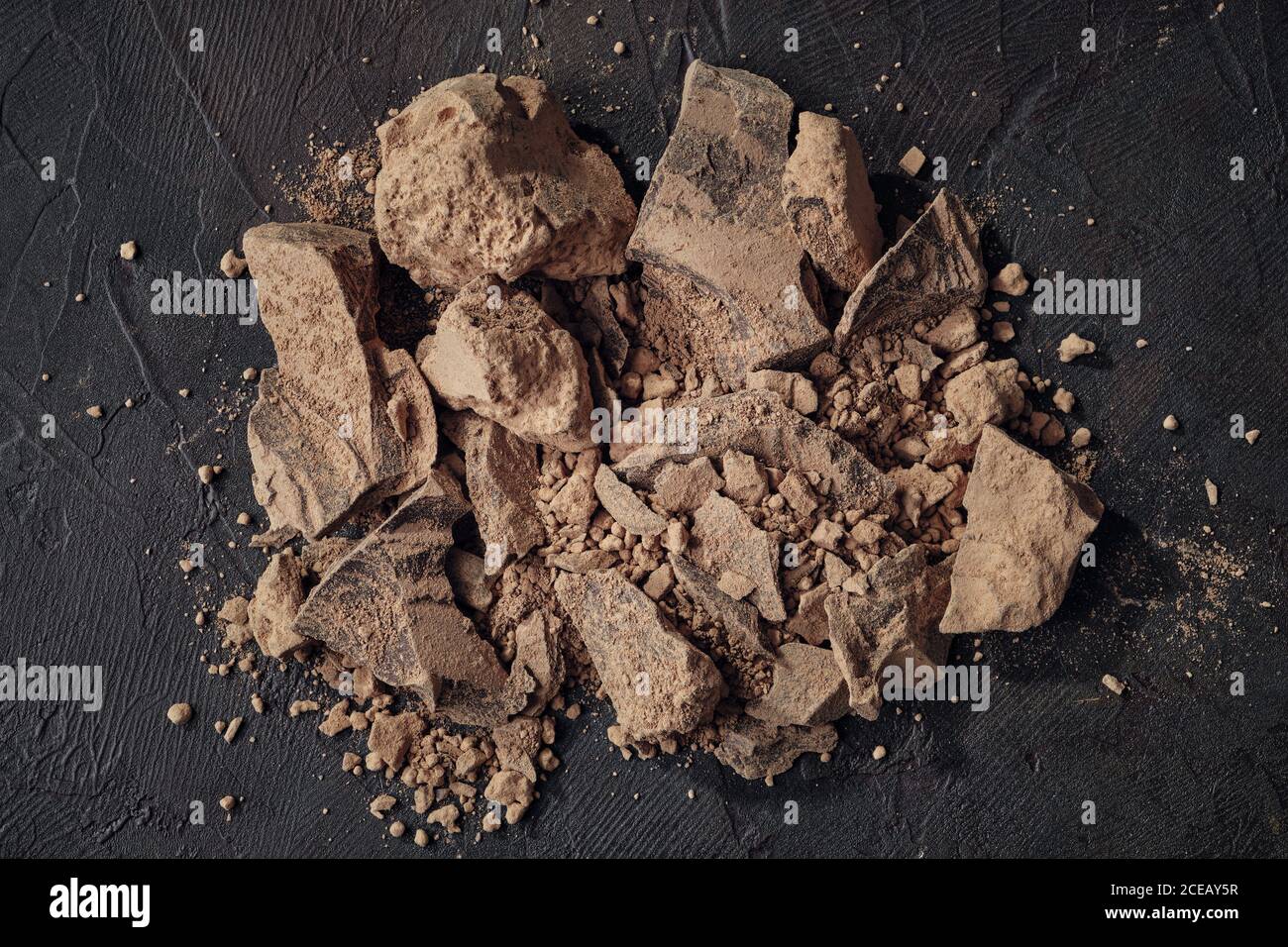 Stücke geriebener Kakao. Naturschokoladenklumpen auf dunklem Hintergrund, Draufsicht. Stockfoto