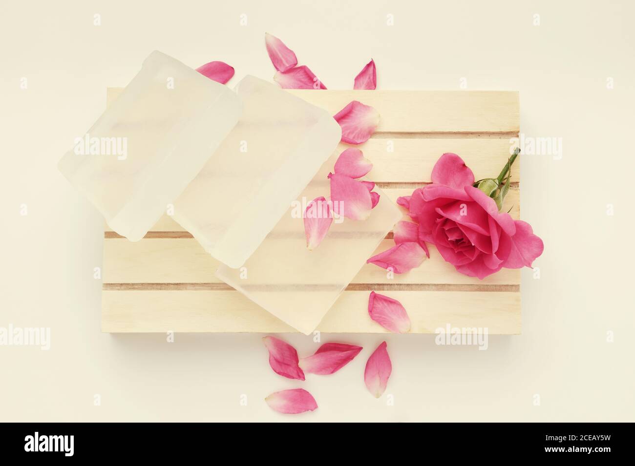 Seifenstück und Rosenblume. Basis für die Herstellung von Seife und rosa Rose Knospe auf Holzpalette. Draufsicht. Stockfoto