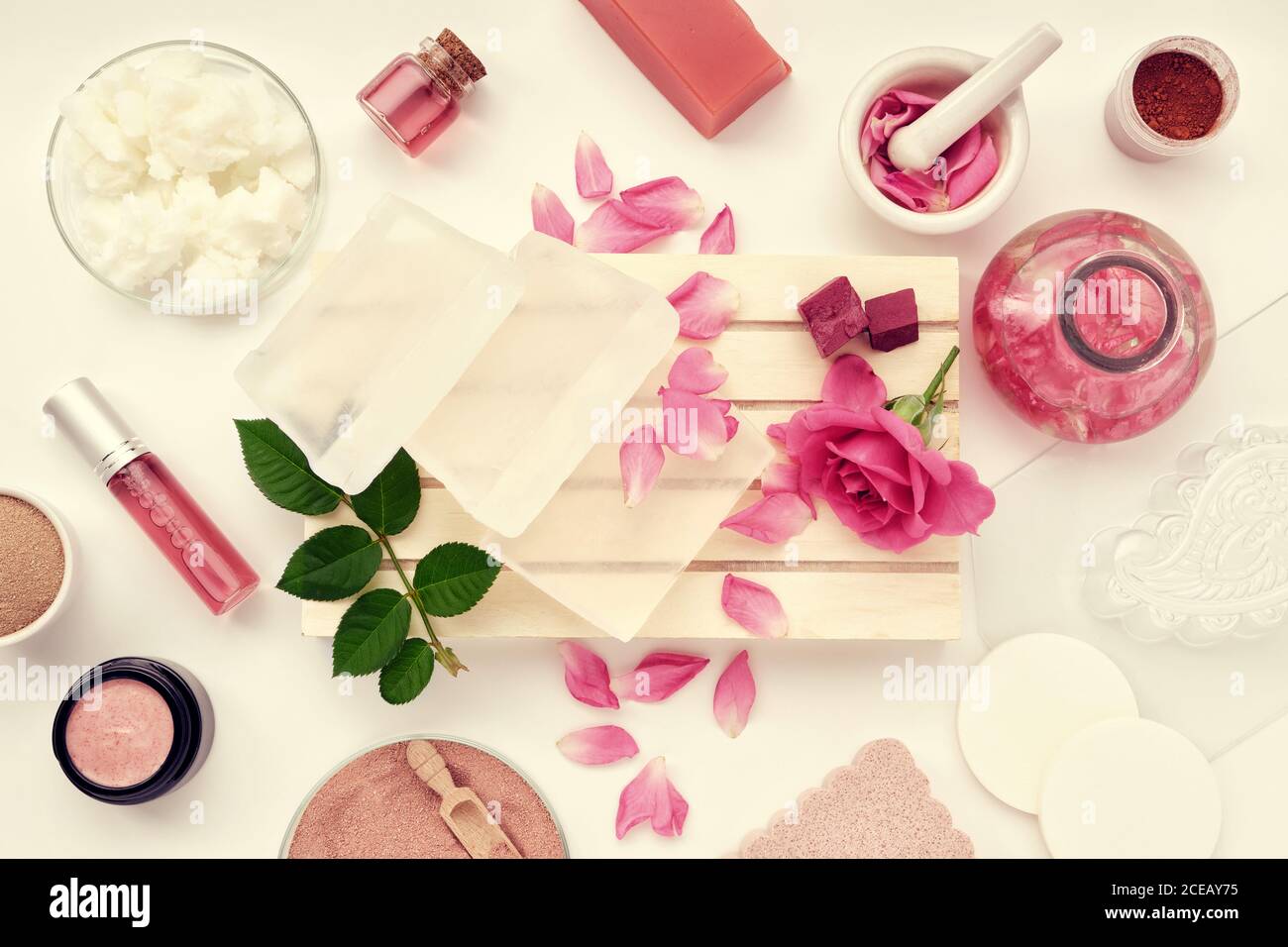 Basis für die Herstellung von Seife, Glas mit hausgemachten feuchtigkeitsspendenden Creme, Rosenblüte, infundiertes Wasser oder ätherische Ölflasche, Kokosöl, Rosenmischung oder aromatisierte wa Stockfoto
