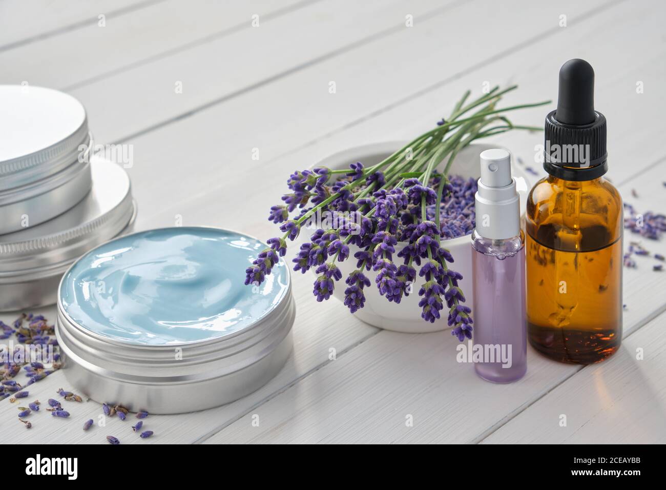 Natürliche Lavendelcreme, Lavendelblüten, Tropfflasche mit ätherischem Lavendelöl und parfümiertes Wasser oder Hydrolat in einer Sprühflasche. Stockfoto