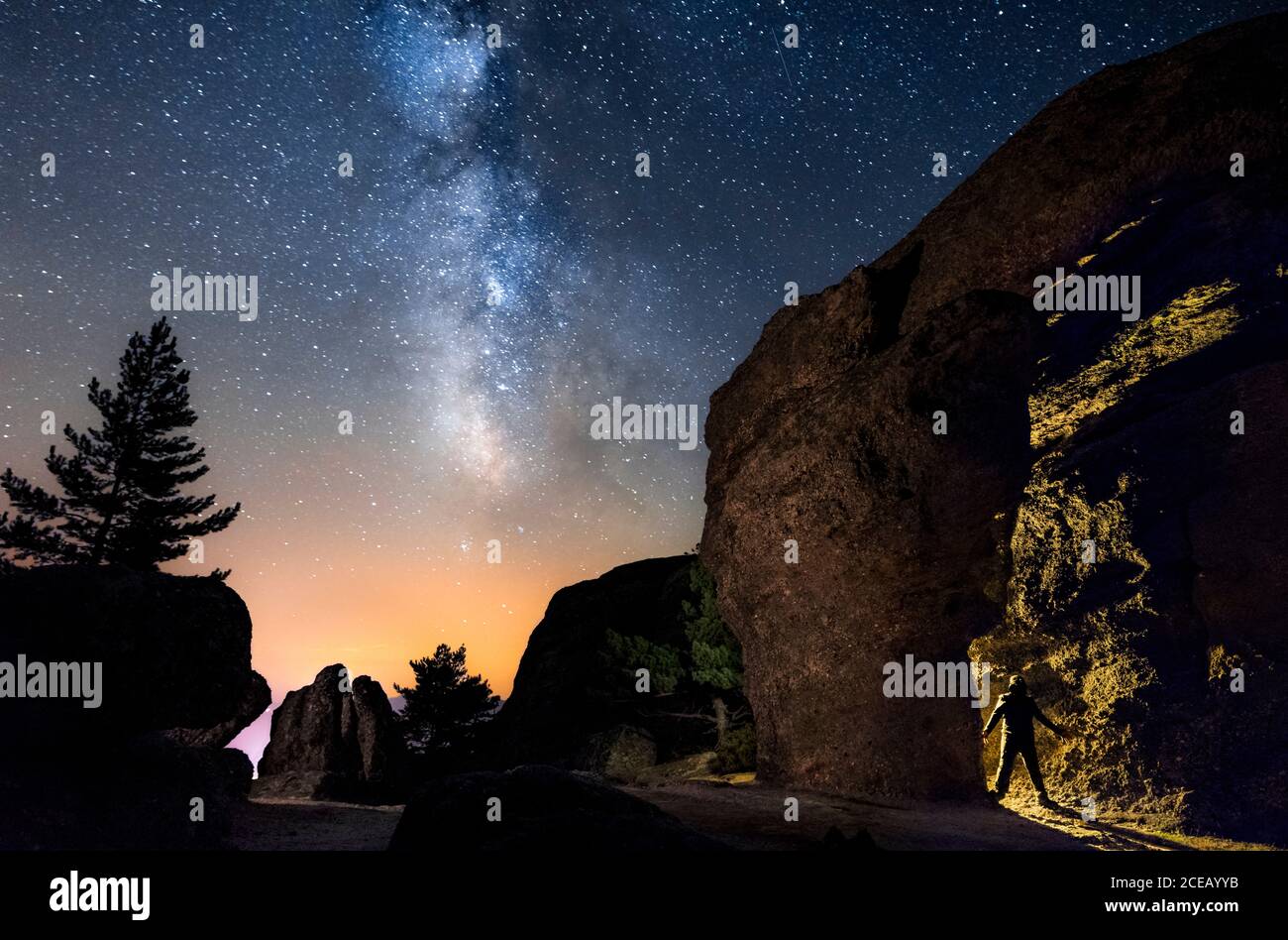 Silhouette eines Mannes in der Nacht, der eine Höhle im Berg mit einer Fackel unter einer erstaunlichen Milchstraße erkundet. Soria, Spanien Stockfoto