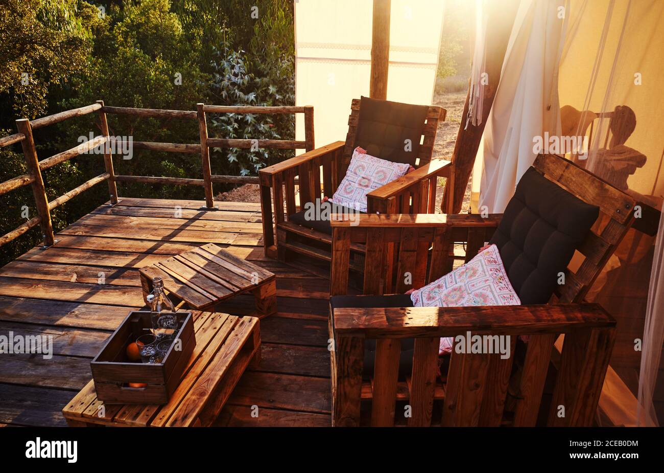 Holzstühle mit Kissen im Zelt bei Sonnenuntergang Stockfoto