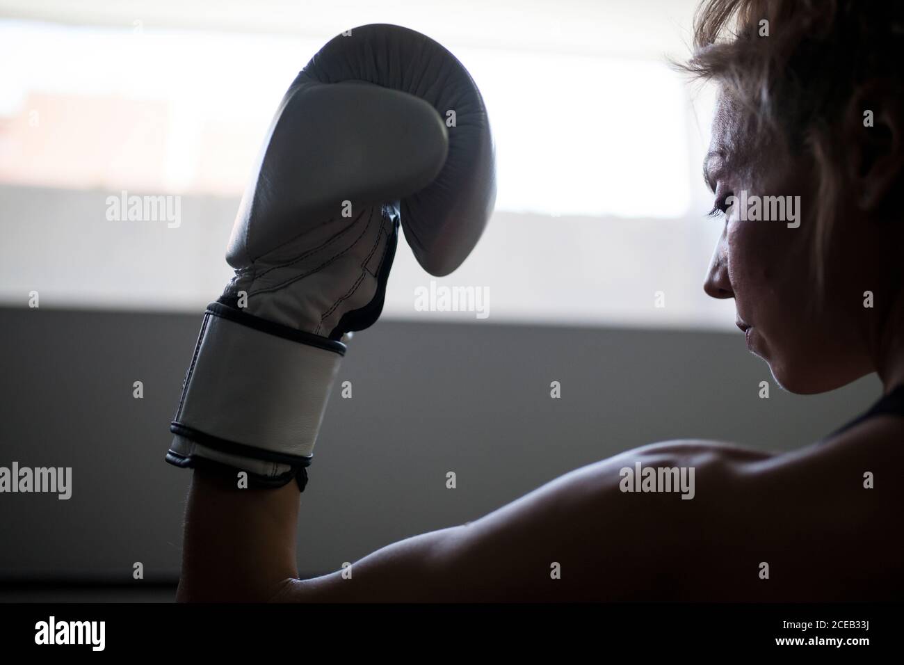 Muskulöse Frau zeigt Bizeps in Sportgeräten und bleibt in Schatten Stockfoto