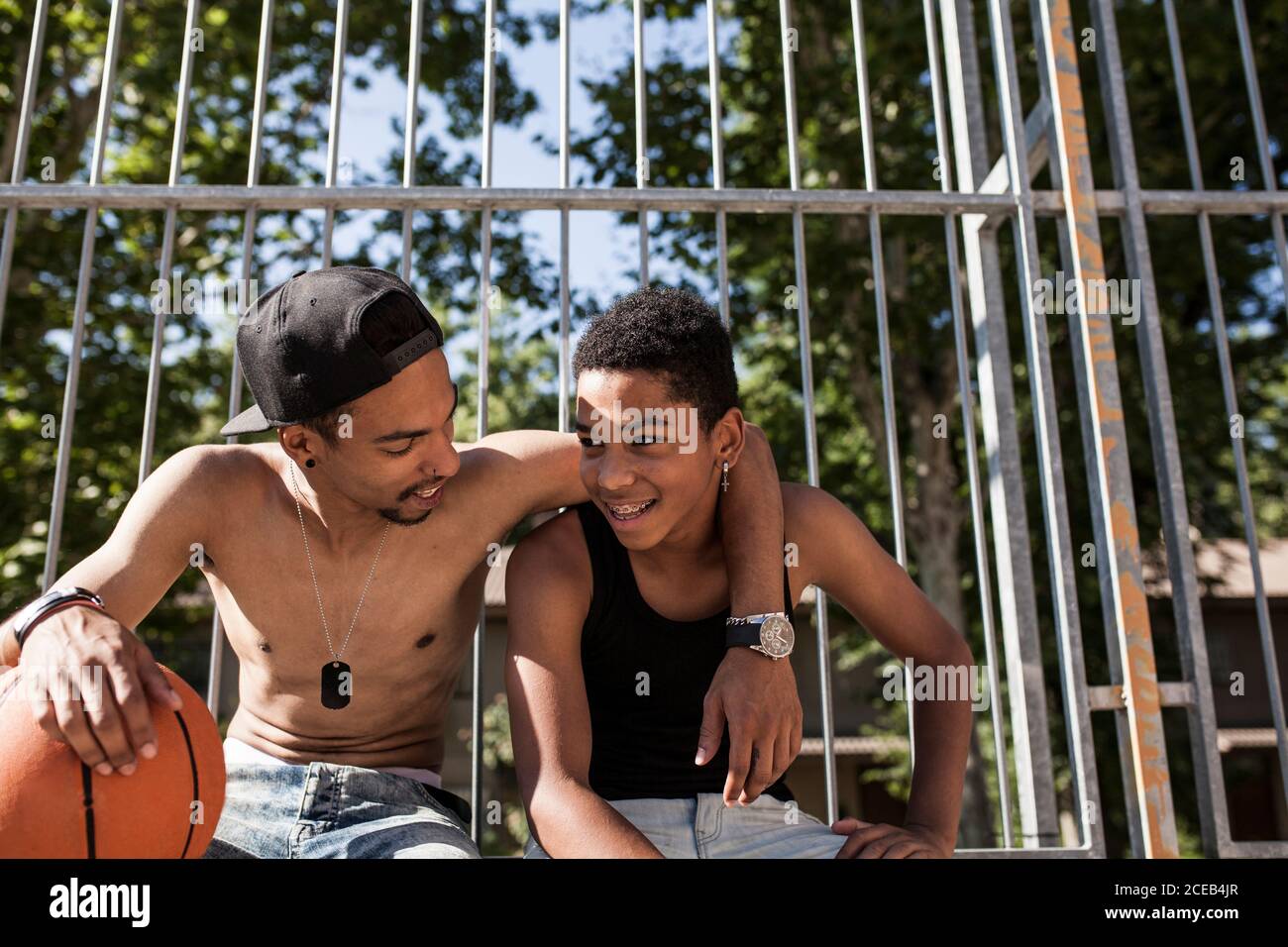 Afro-junge Brüder spielen Basketball auf dem Hof ihrer Nachbarschaft lächelnd und umarmt Stockfoto