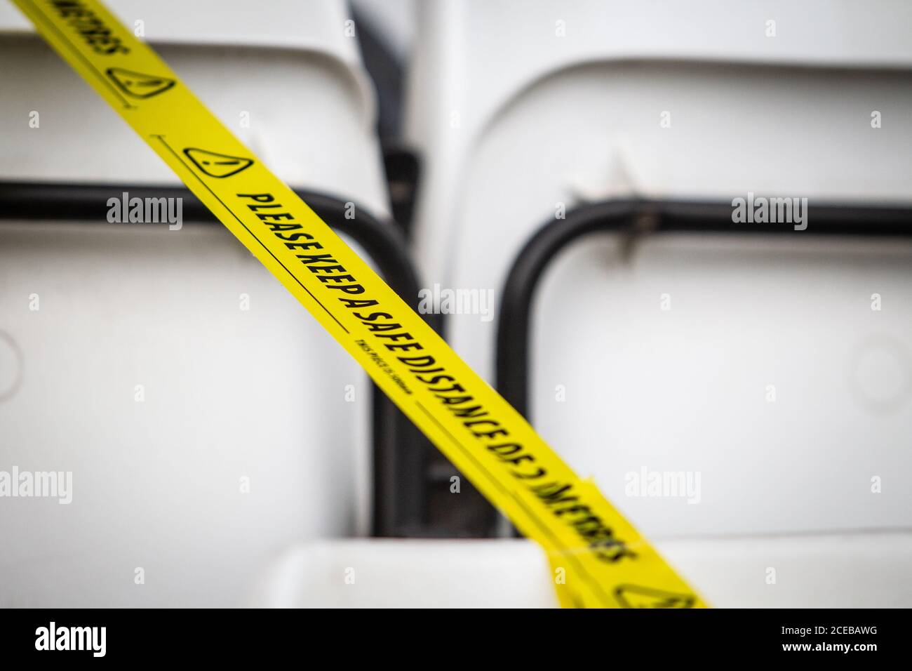 Nahaufnahme eines Sicherheitsbandes, das über die Sitze im Sportstadion gespannt ist und Zuschauer, Fans und Mitarbeiter während der Pandemie von Covid 19 sozial distanziert hält. Stockfoto
