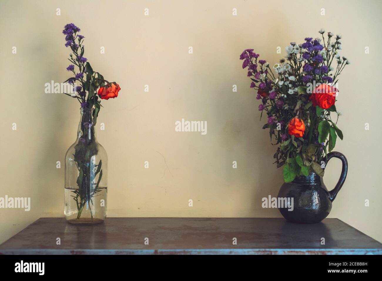 Zwei Vasen mit schönen Blumensträußen stehen auf dem Tisch in der Nähe Helle Wand Stockfoto