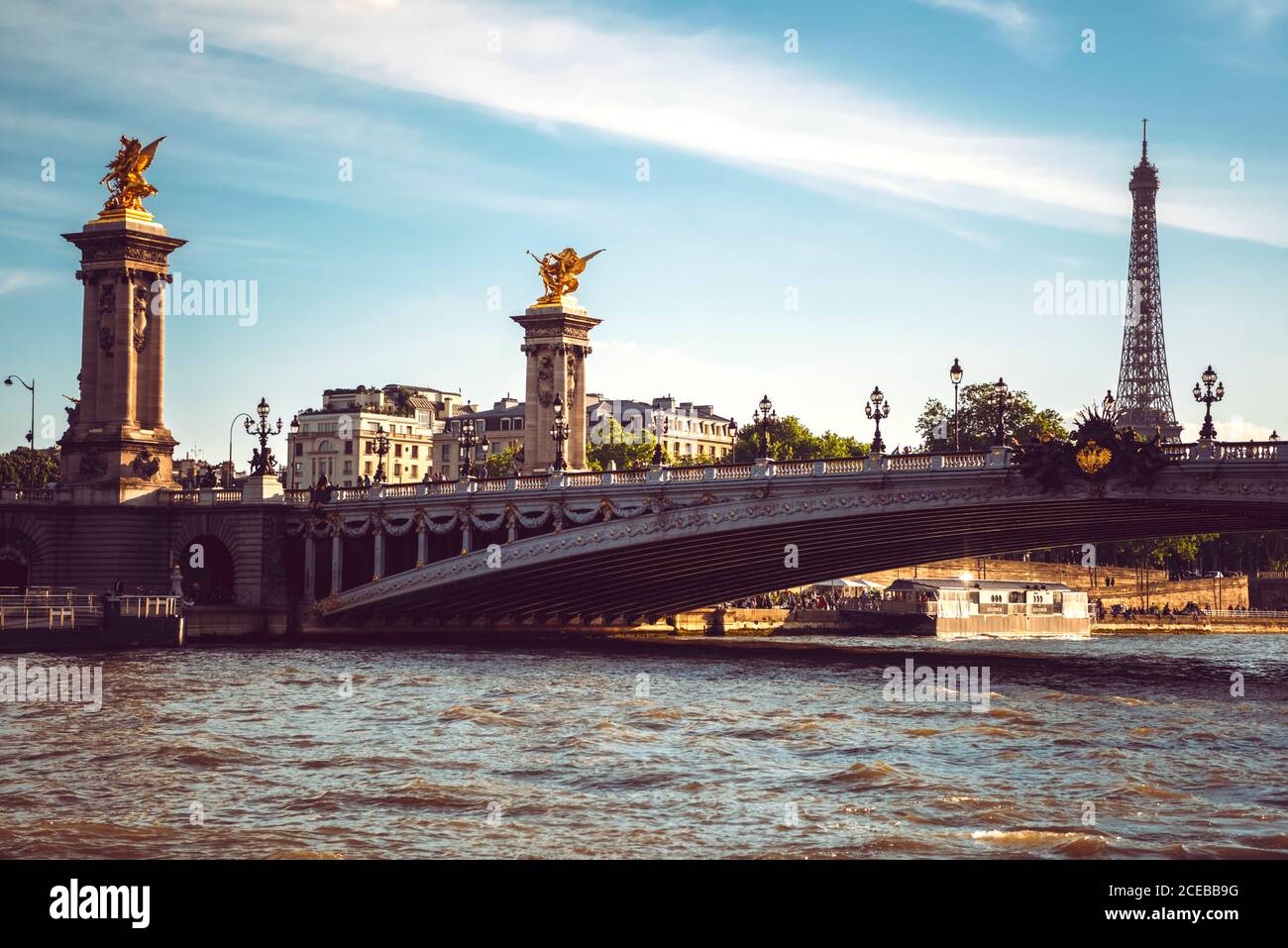 Große Flussbrücke mit Laternen unter blau bewölktem Himmel in Paris Stockfoto
