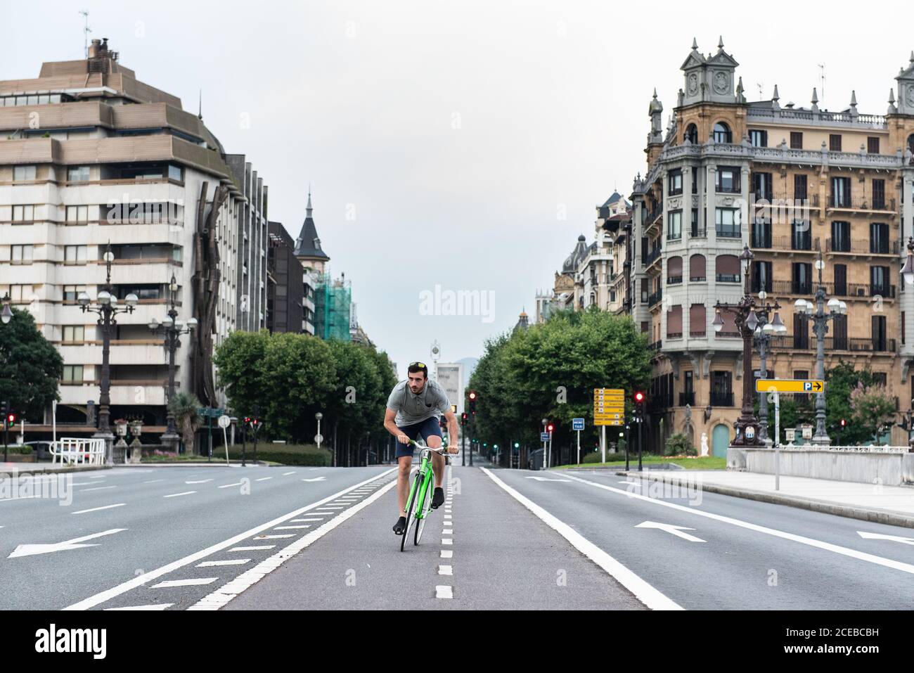 Junger Mann, der auf leerer Straße auf dem grünen Fahrrad in Europa reitet Stadt Stockfoto