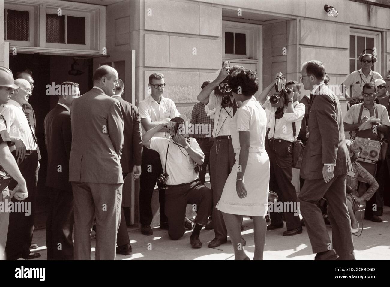 Vivian Malone, eine der ersten Afroamerikaner, die an der Universität von Alabama teilnahmen, geht durch eine Menschenmenge, die Fotografen, Mitglieder der Nationalgarde und den stellvertretenden US-Generalstaatsanwalt Nicholas Katzenbach umfasst, um das Foster Auditorium zu betreten, um sich für den Unterricht am 11. Juni 1963 anzumelden. Stockfoto