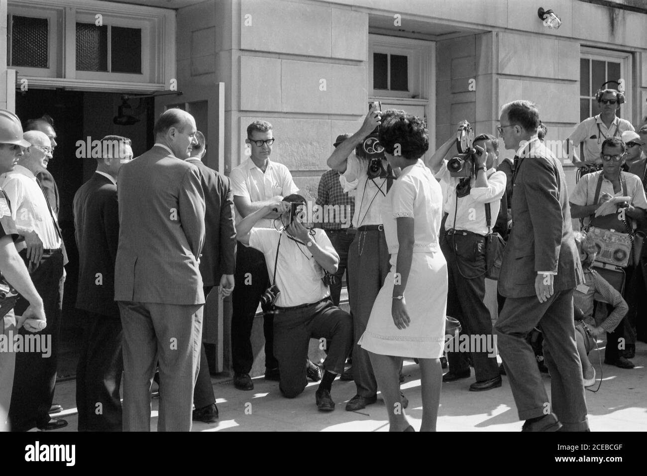 Vivian Malone, eine der ersten Afroamerikaner, die an der Universität von Alabama teilnahmen, geht durch eine Menschenmenge, die Fotografen, Mitglieder der Nationalgarde und den stellvertretenden US-Generalstaatsanwalt Nicholas Katzenbach umfasst, um das Foster Auditorium zu betreten, um sich für den Unterricht am 11. Juni 1963 anzumelden. Stockfoto