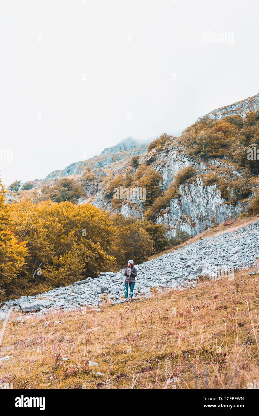 Person mit Rucksack auf Wiese, wolkigen Himmel und Blick auf Berge mit Wald in Isoba, Kastilien und Leon, Spanien Stockfoto