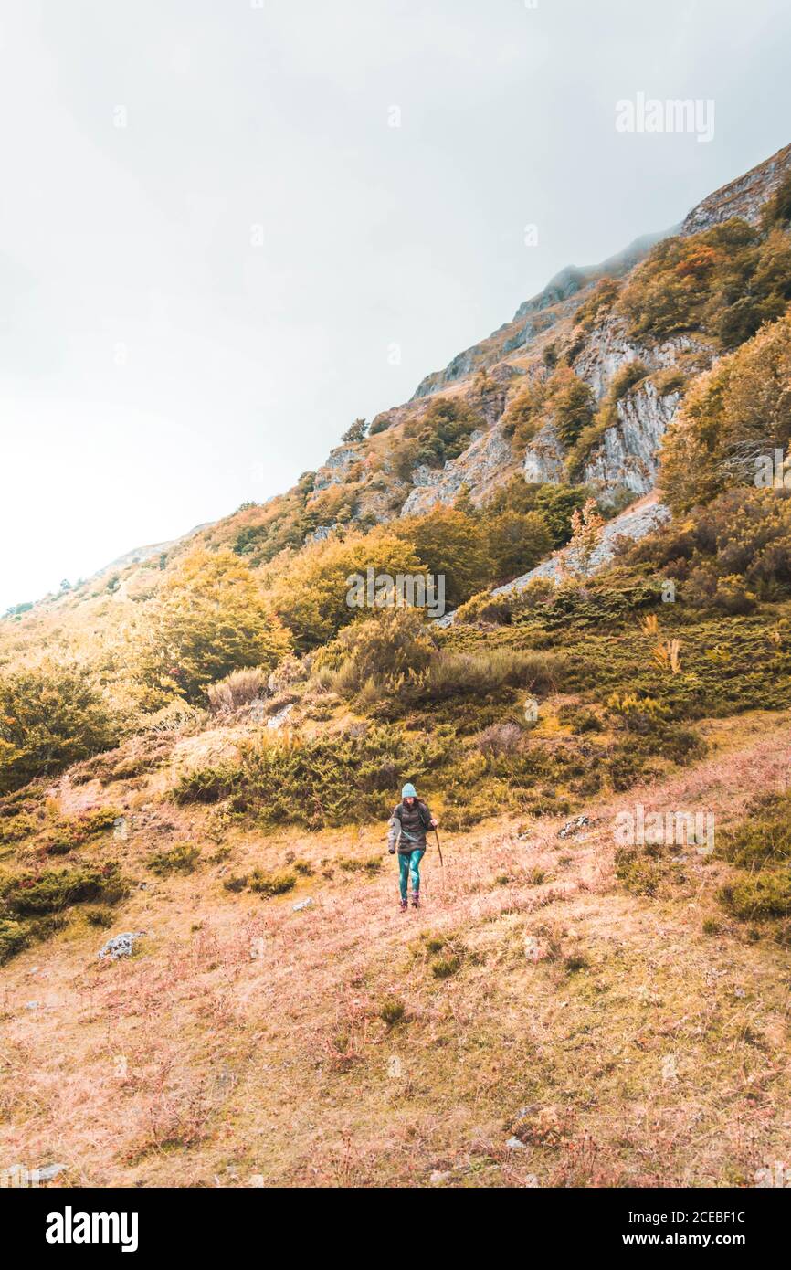 Person mit Rucksack auf Wiese, wolkigen Himmel und Blick auf Berge mit Wald in Isoba, Kastilien und Leon, Spanien Stockfoto