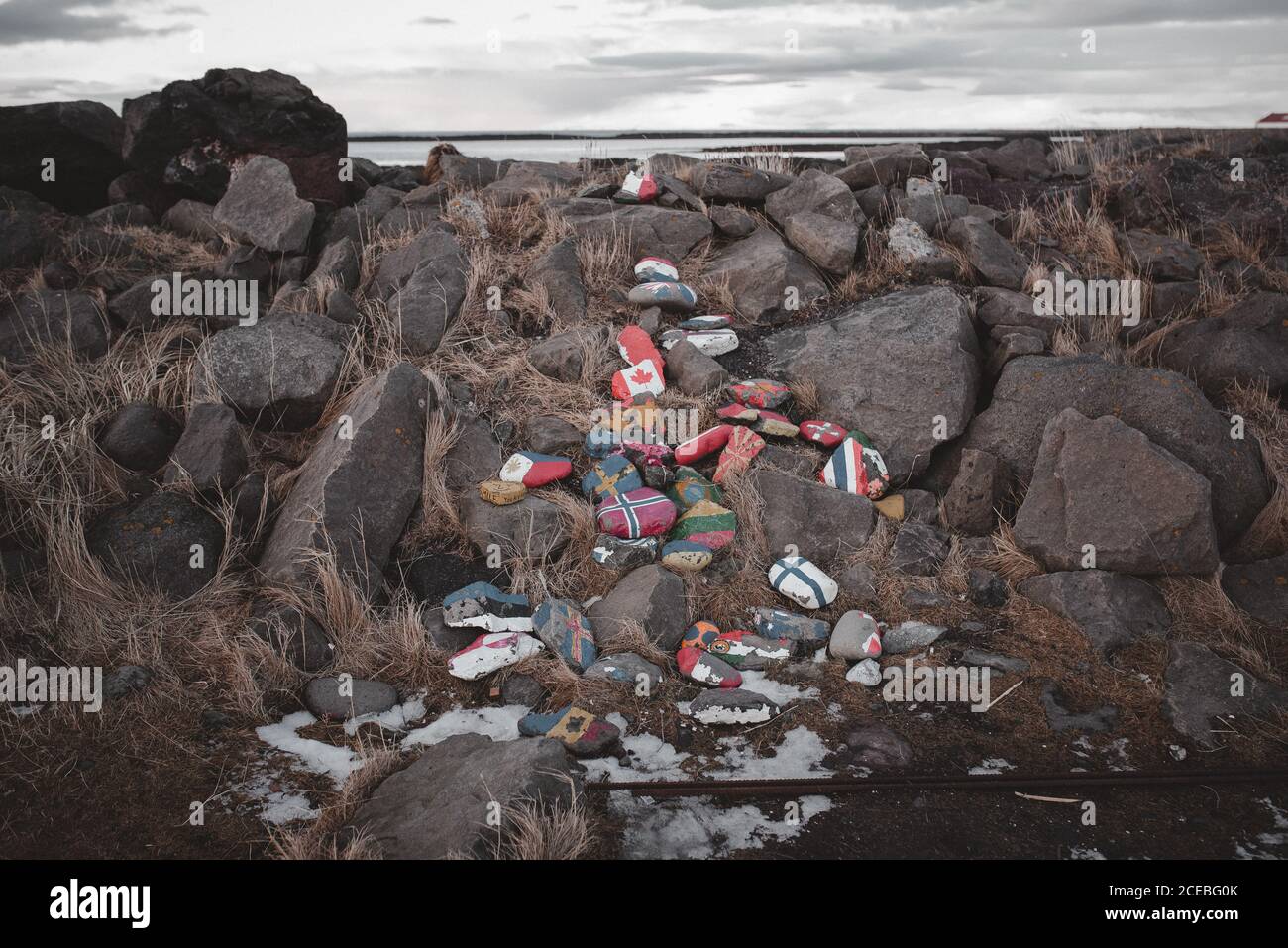 Bündel von glatten Felsen mit bemalten Fahnen verschiedener Länder Liegt an steinerner Küste in Island Stockfoto